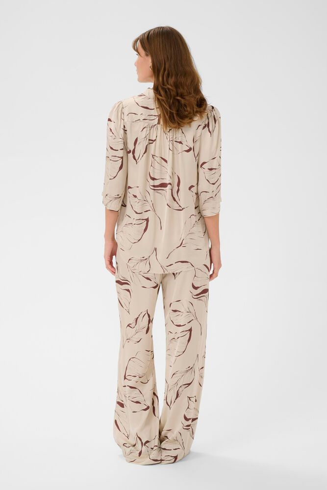 Rückansicht der Soaked Clero Flared Printed Pants - Oatmeal Leave Print mit fließendem, ausgestelltem Bein