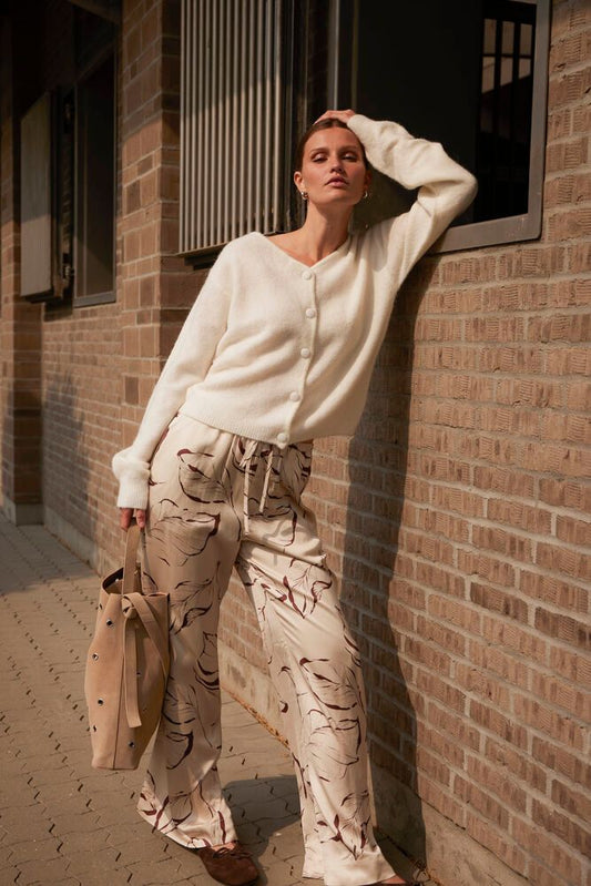 Gestylter Look der Soaked Clero Flared Printed Pants - Oatmeal Leave Print kombiniert mit Strickjacke für einen modernen Alltagsstil