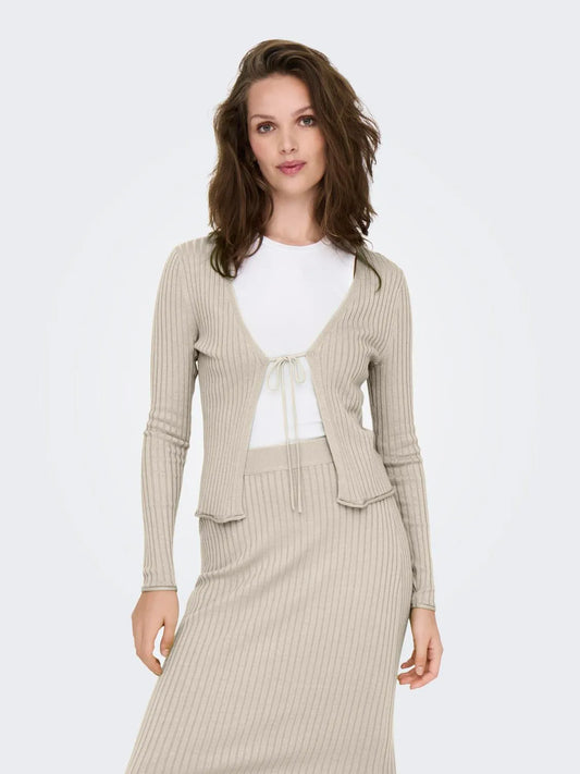 Model trägt einen beigen Rippstrick-Cardigan von Only in der Farbe birch mit Bindeband, kombiniert mit einem passenden Rock und einem weißen Shirt.