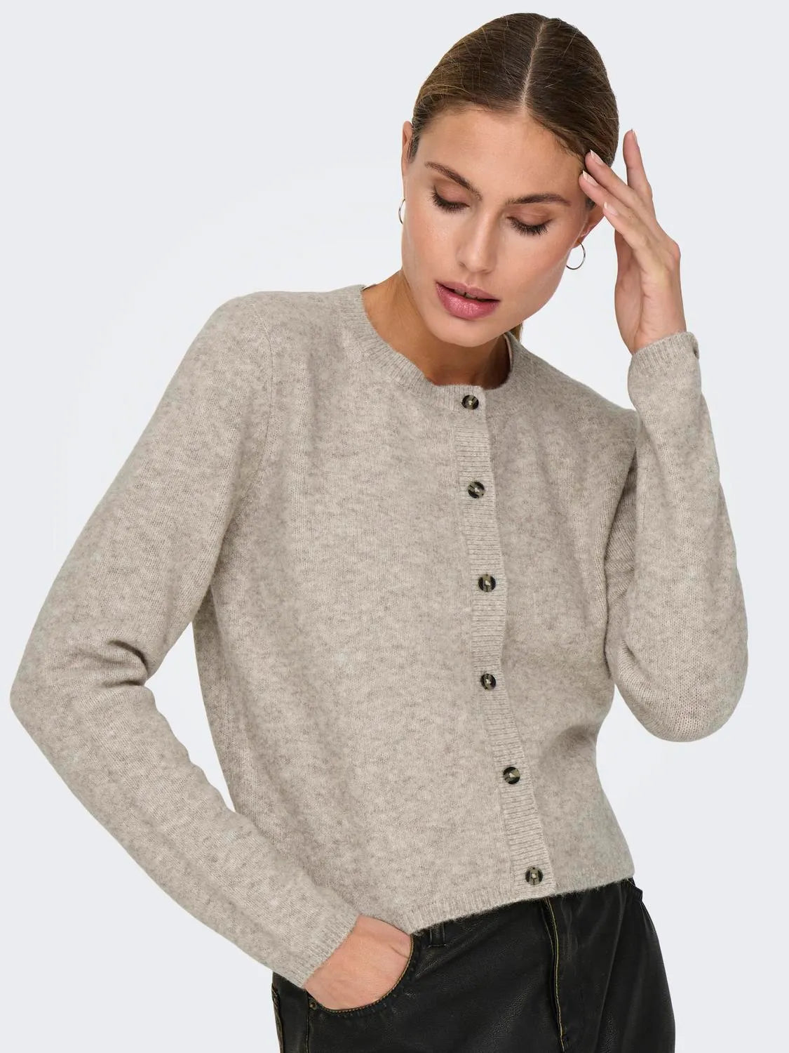 Model trägt einen beigen Strick-Cardigan mit Rundhalsausschnitt und Knopfleiste von JDY.