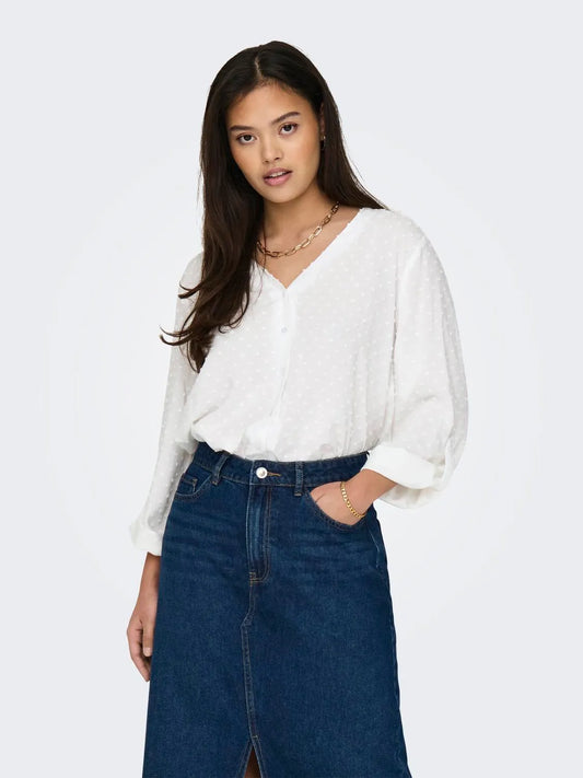 Model trägt eine locker sitzende weiße Bluse von JDY mit feiner Struktur, V-Ausschnitt und Knopfleiste, kombiniert mit schwarzer Hose.