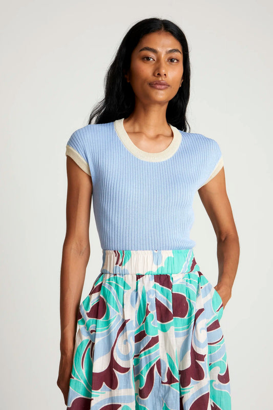 Das Wild Pony Two Tone Knit Top in Hellblau mit geripptem Design und kontrastierendem Rundhalsausschnitt in Weiß. Stylisch kombiniert mit einem gemusterten Rock.