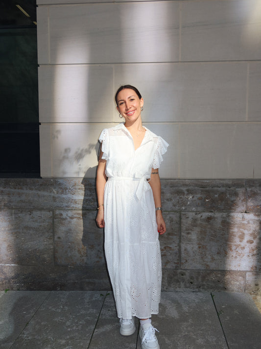 celincarolin Frau trägt das Breeze Dress White mit femininer Lochstickerei und Taillengürtel, perfekt für warme Sommertage.