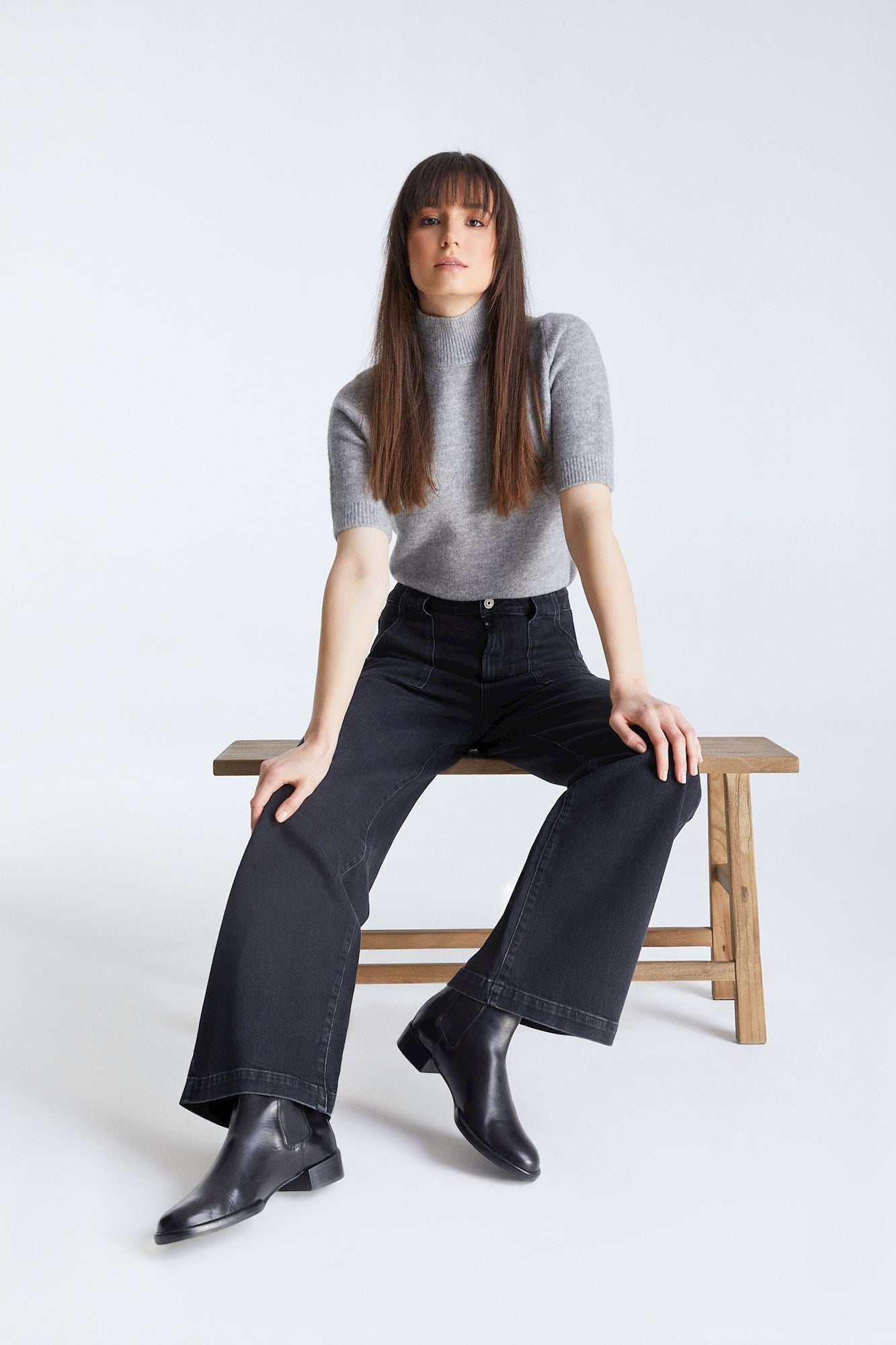 Frau sitzt auf einer Bank und trägt COJ Lulu Wide Leg Black Vintage Jeans, lässige Pose mit Fokus auf den weiten Schnitt.