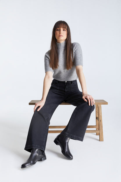 Frau sitzt auf einer Bank und trägt COJ Lulu Wide Leg Black Vintage Jeans, lässige Pose mit Fokus auf den weiten Schnitt.