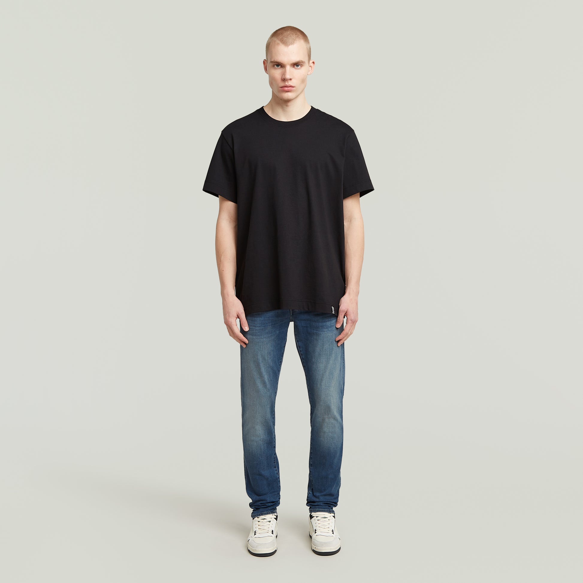 Model trägt die G-Star 3301 Slim Jeans mit mittelhohem Bund und klassischem 5-Pocket-Design, kombiniert mit einem schwarzen T-Shirt.