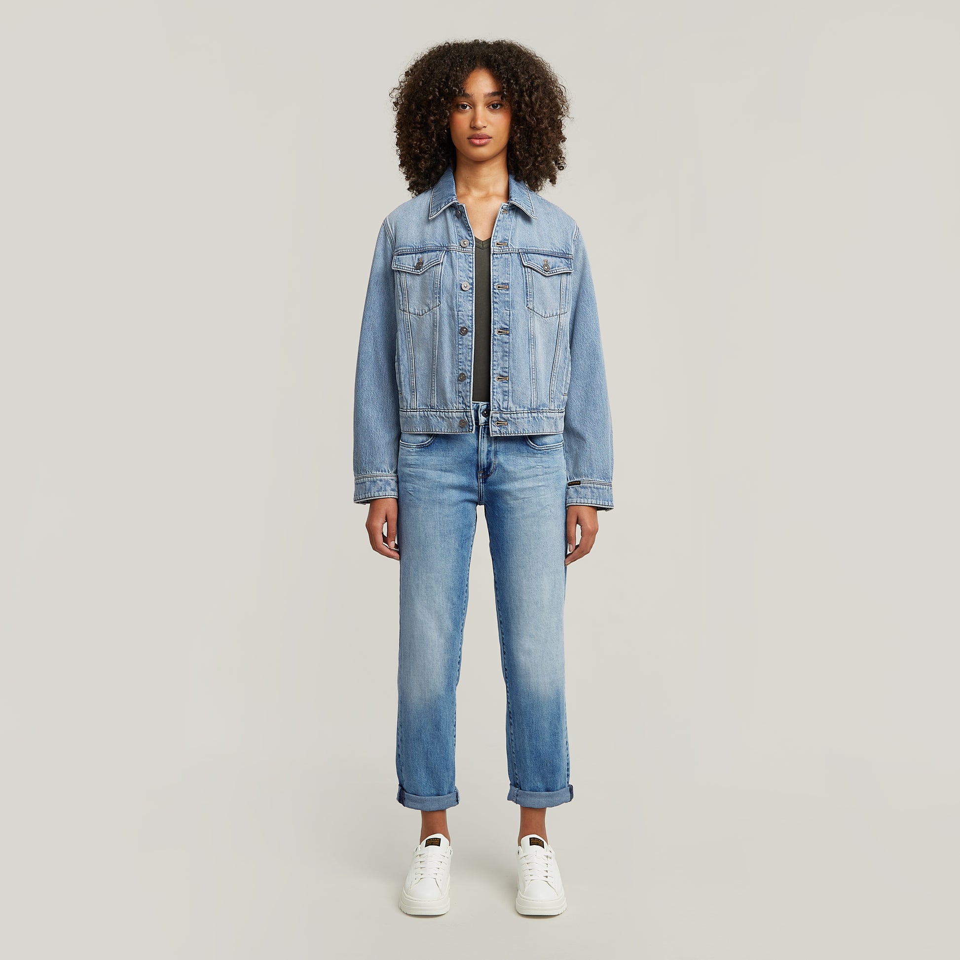Ganzkörperansicht einer Frau, die die G-Star Kate Boyfriend Jeans in Light Indigo Aged mit hochgekrempeltem Saum und einer Jeansjacke trägt.