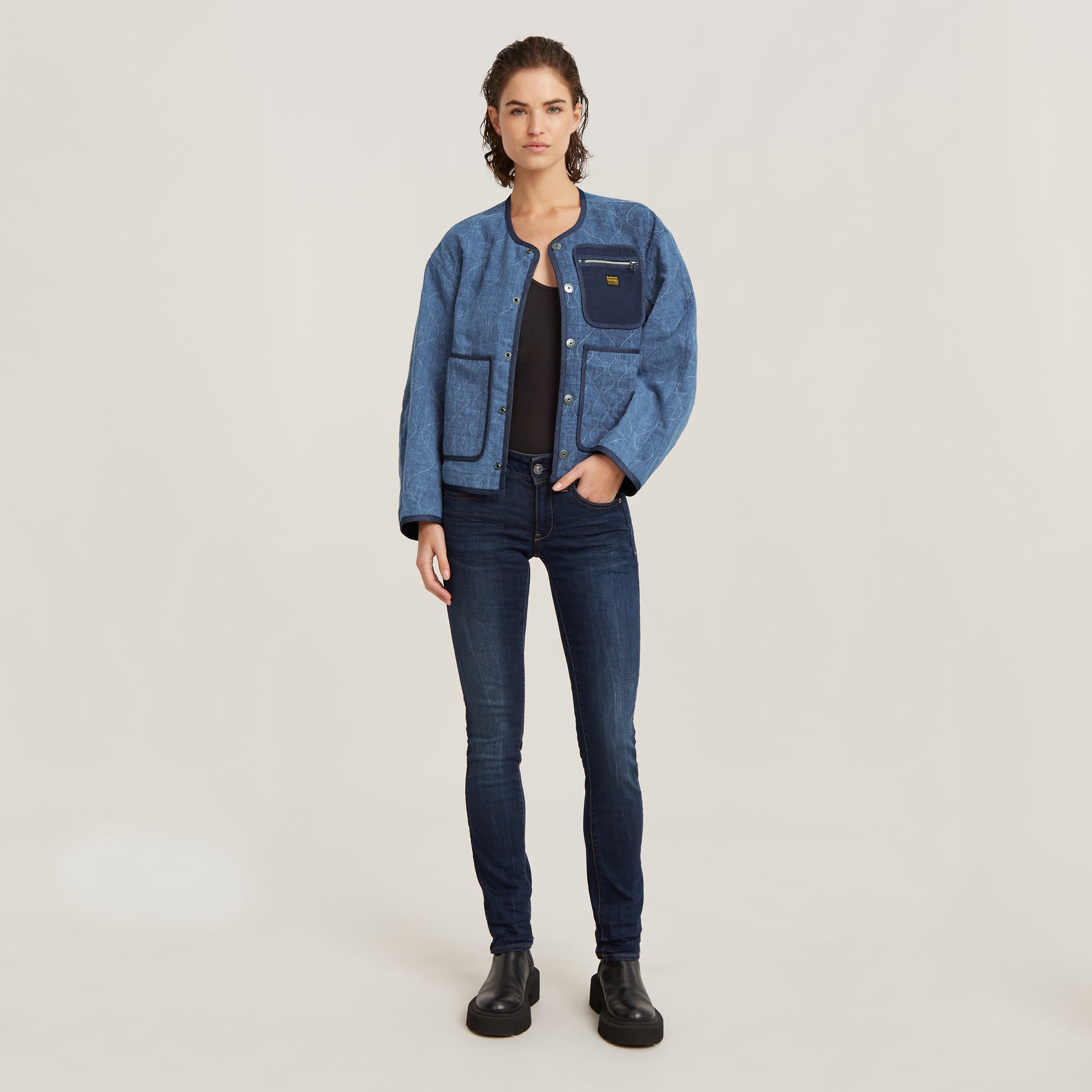 Model trägt die G-Star Midge Mid Waist Straight Dark Aged Jeans in dunkler Waschung kombiniert mit Jacke und Boots
