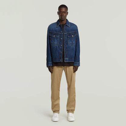 Modell trägt G-Star Morry Tapered Chino Safari mit dunkler Denimjacke und weißen Sneakers.

