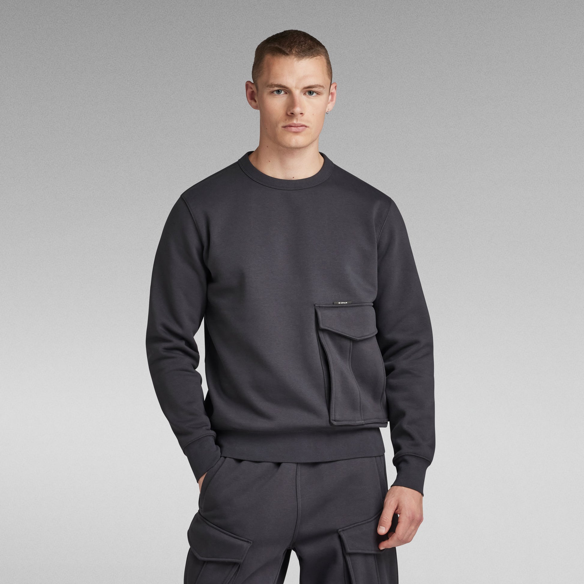 G-Star Pullover Cargo R Sw in Anthrazit mit Tasche auf der Vorderseite, Modell frontal.