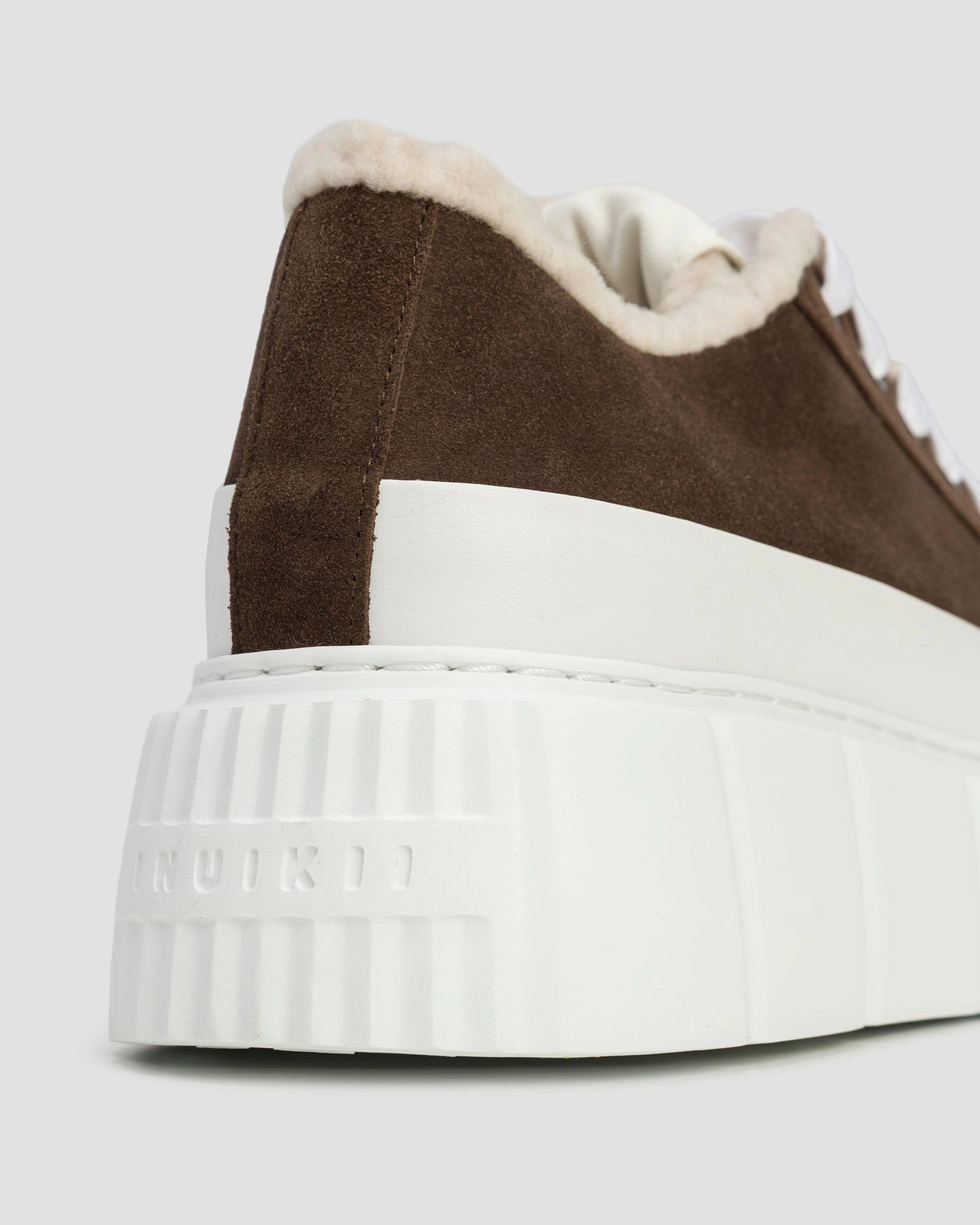 Inuikii Matilda Curly Dark Brown – Detailaufnahme der Ferse mit geprägtem Inuikii-Logo und strukturierter Plateausohle.