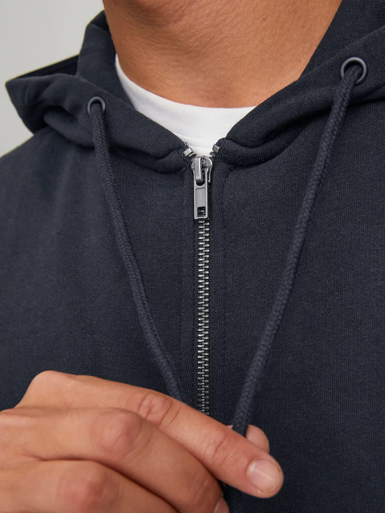 Nahaufnahme des Jack&Jones Bradley Sweat Zip Hood Black mit Metallreißverschluss und Kapuzenschnüren.