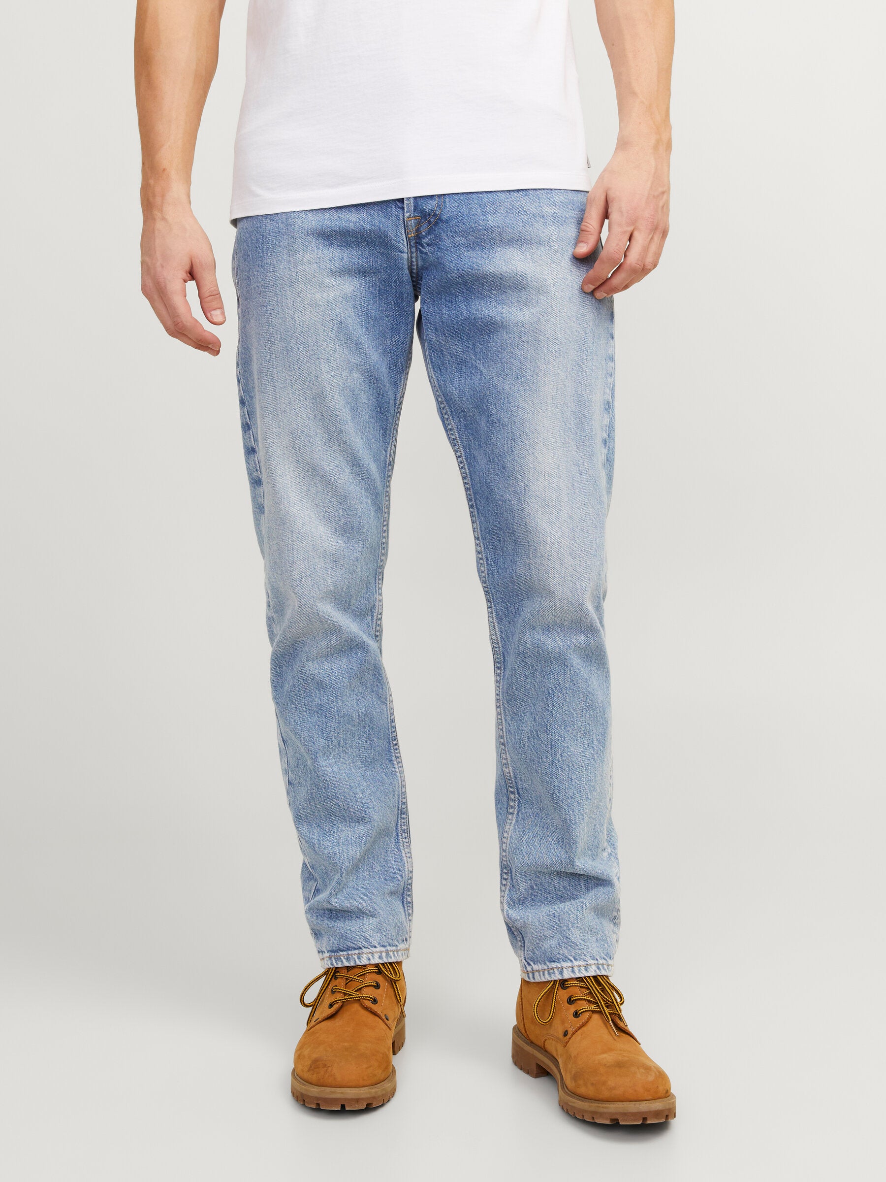 Vorderansicht der Jack & Jones Chris 981 Relaxed Blue Denim Jeans, getragen von einem Mann in einem weißen T-Shirt mit braunen Schuhen.