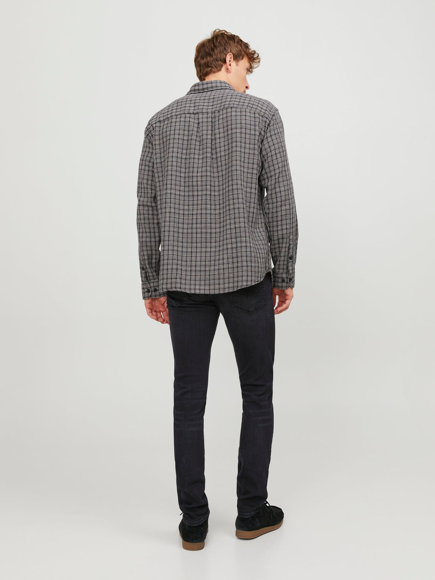 Rückansicht der Jack & Jones Glenn Slim Black Denim, kombiniert mit einem karierten Hemd, präsentiert auf einem Model.