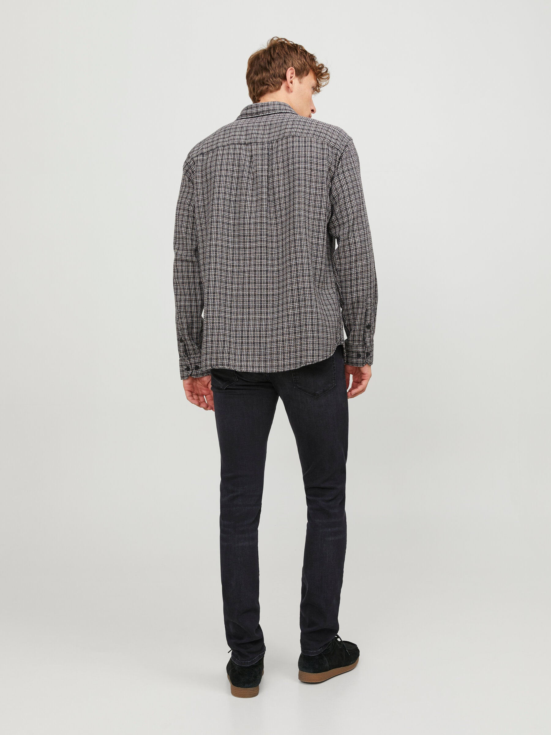 Rückansicht der Jack & Jones Glenn Slim Black Denim, kombiniert mit einem karierten Hemd, präsentiert auf einem Model.
