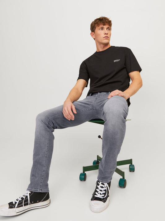 Model, das die Jack & Jones Glenn Slim Grey Denim trägt und lässig auf einem Bürostuhl sitzt.