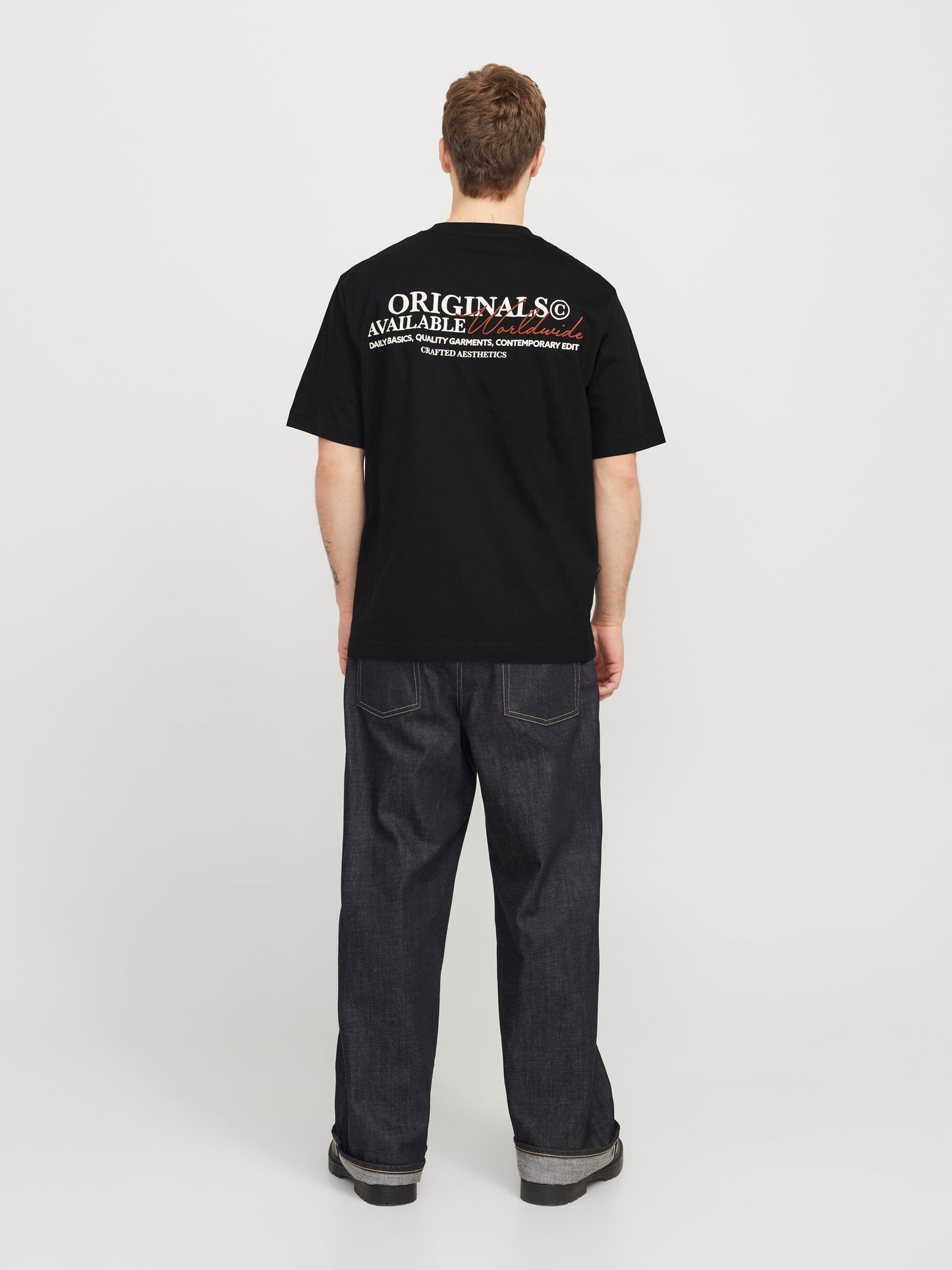 Ganzkörperansicht des Jack&Jones Rislington T-Shirts in Schwarz, kombiniert mit dunklen Jeans. Die Rückengrafik ist gut sichtbar.