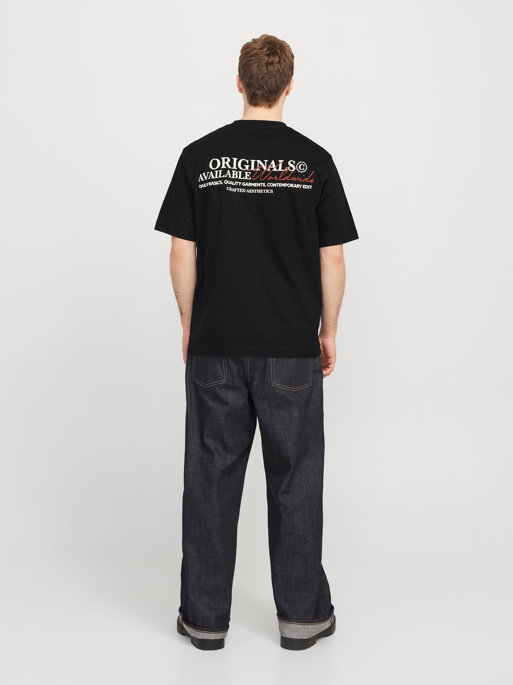 Ganzkörperansicht des Jack&Jones Rislington T-Shirts in Schwarz, kombiniert mit dunklen Jeans. Die Rückengrafik ist gut sichtbar.