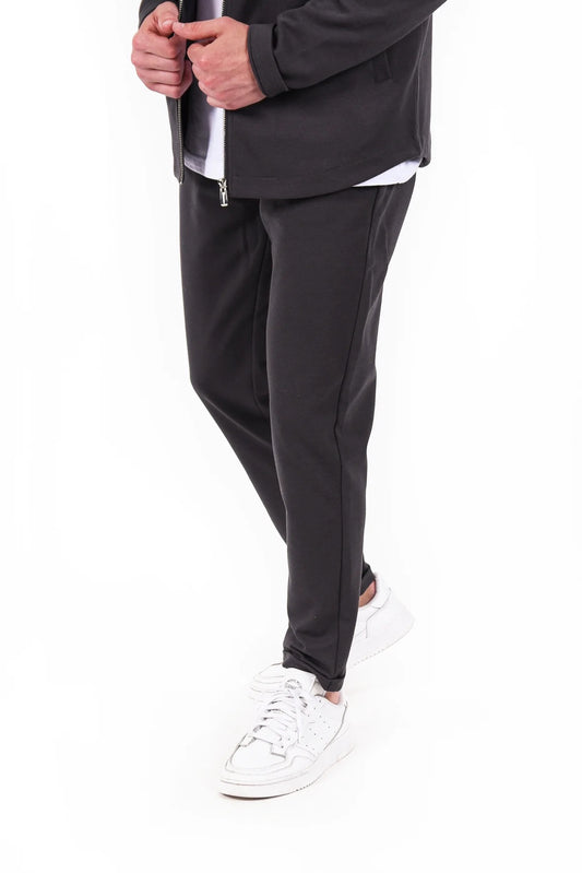 Kleinigkeit Albert Feinstein Asphalt Grey – Moderne Jogginghose in Dunkelgrau mit schmaler Passform, kombiniert mit weißen Sneakern.