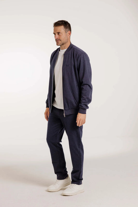 Mann trägt den Kleinigkeit Peter Maffein Blouson Navy Blue mit passender Hose und weißen Sneakern in einer neutralen Studioaufnahme.