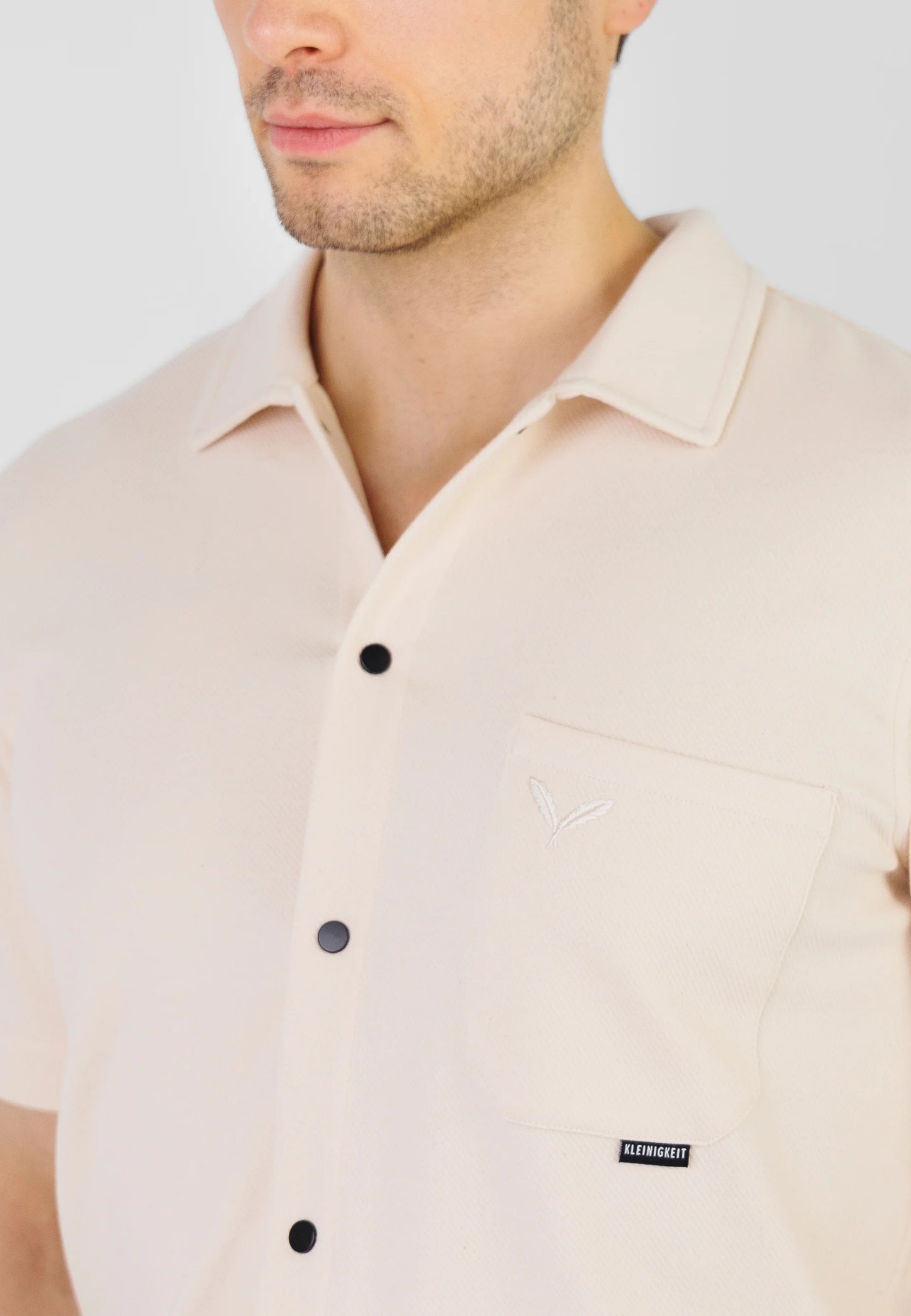 Detailaufnahme der Brusttasche und Knopfleiste beim Kleinigkeit Relaxel Schulz Shirt - Frappe mit dezentem Kleinigkeit Label.