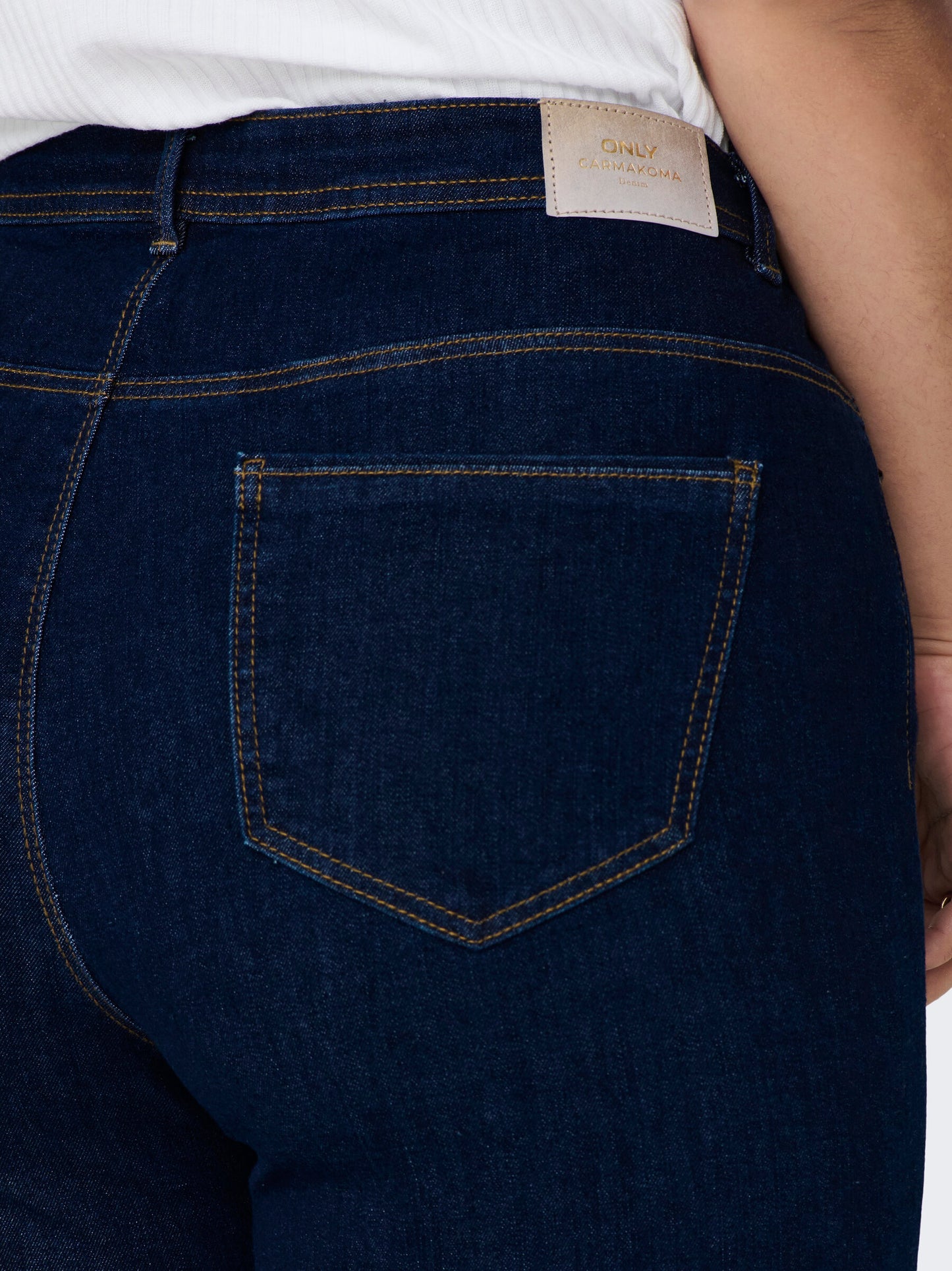 Nahaufnahme der Gesäßtaschen und Gürtelschlaufen der Only Carmakoma Carsally Flared Jeans in Dunkelblau. Perfekt für einen stilvollen Alltagslook.