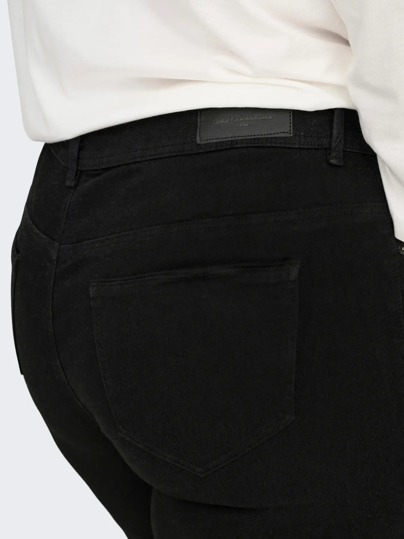 Detailaufnahme des Rückteils der Only Carmakoma Sally - High Waist Flared Jeans in Schwarz mit Label und Gesäßtasche.