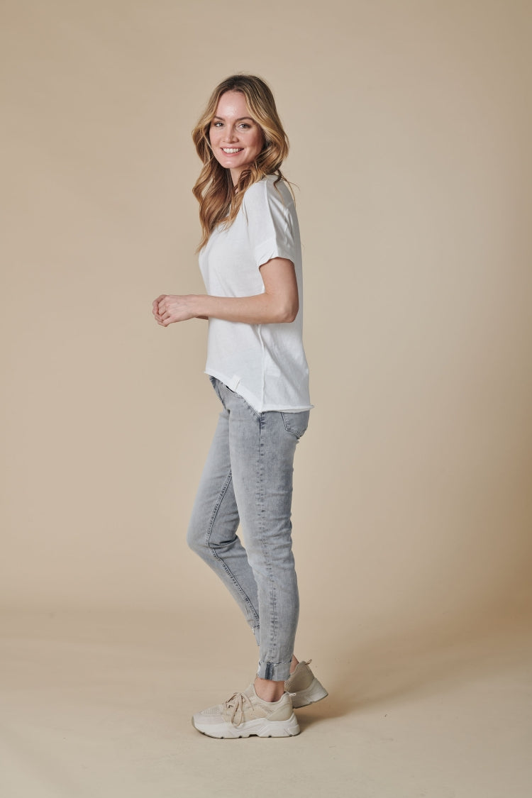 Seitenansicht des Zhrill Rahel T-Shirts in Weiß, kombiniert mit grauer Jeans und Sneakern für einen casual Look.